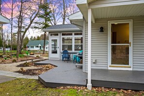 A house with a covered porch, a dining area with outdoor furniture, and a large window.