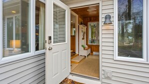 A wooden interior with a door leading to a porch, a small seating area, and a lamp. - Pet Friendly Cottage in Egg Harbor-Close to Beach (Egg Harbor)