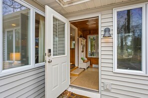 A wooden interior with a door leading to a porch, a small seating area, and a lamp.