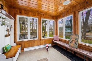 A wooden cabin with large windows, a bench, and a small motorcycle.