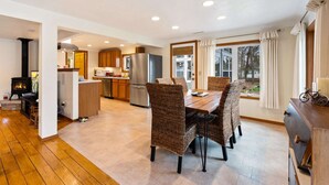 A modern kitchen with a dining area, wooden flooring, and a large window with curtains. - Pet Friendly Cottage in Egg Harbor-Close to Beach (Egg Harbor)