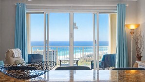 A balcony with a view of the ocean, a ceiling fan, and a table with chairs.