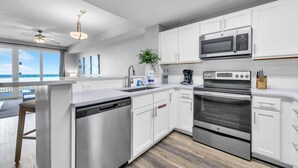 A modern kitchen with white cabinets, stainless steel appliances, a dishwasher, and a coffee maker.