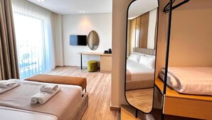 A hotel room with a bunk bed, a desk with a chair, a mirror, and a window with curtains. - Avenue Hotel (Ksamil)