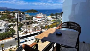 A balcony with a view of a coastal town, a table, and a chair. - Avenue Hotel (Ksamil)