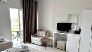 A hotel room with a bed, a sofa, a TV, a desk, and a wardrobe. - Avenue Hotel (Ksamil)