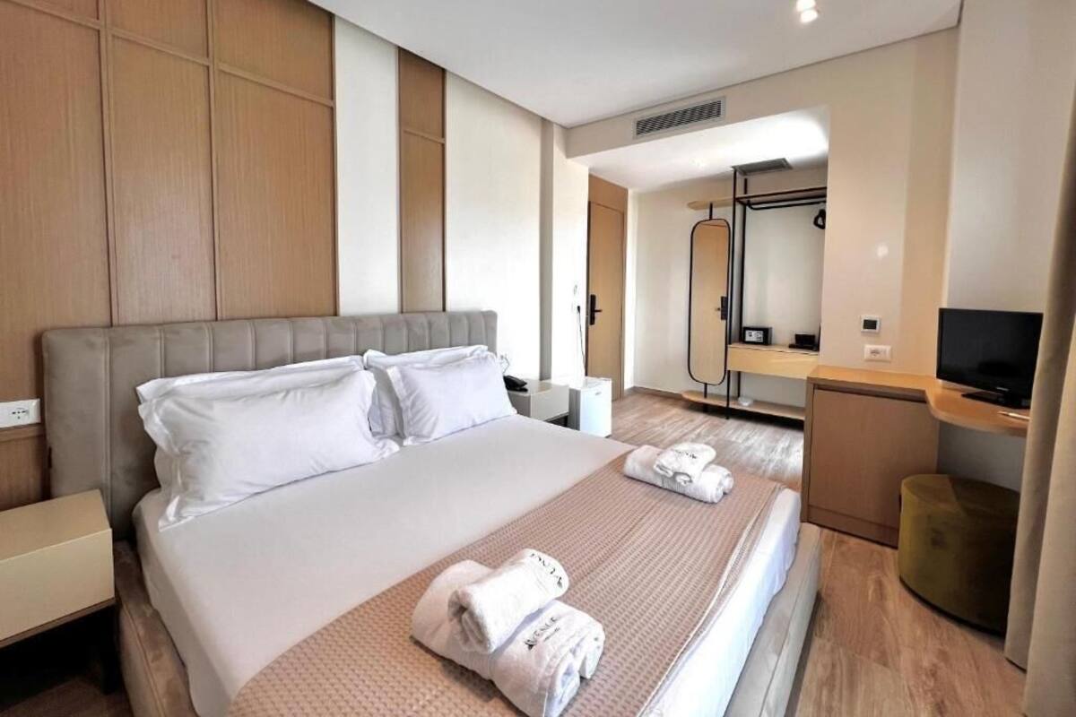 A hotel room with a large bed, a desk with a TV, and a mirror.