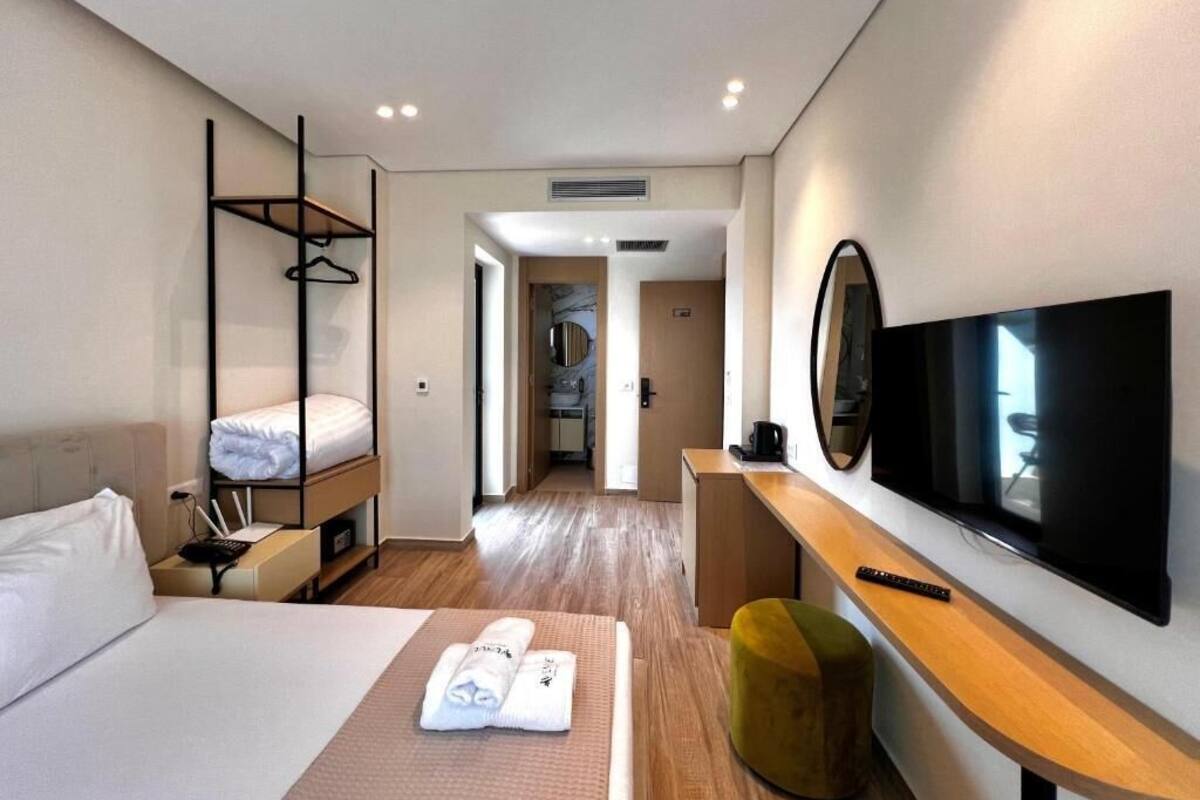 A hotel room with a bed, a TV, a desk, a hanging chair, and a walk-in closet.