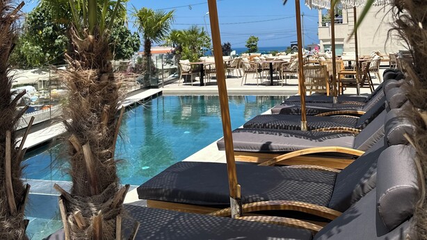 A poolside area with lounge chairs and palm trees. - Avenue Hotel (Ksamil)