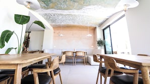 A modern interior with wooden tables and chairs, a textured ceiling, and large windows. - Avenue Hotel (Ksamil)