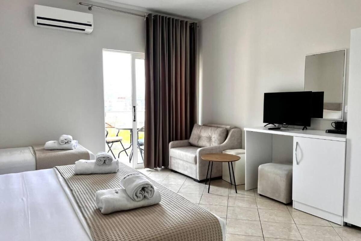A hotel room with a bed, a sofa, a desk with a TV, and a wardrobe.