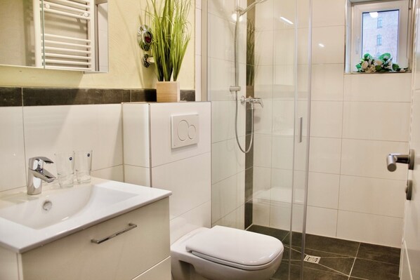 A modern bathroom with a glass-enclosed shower, a white sink with a mirror, and a toilet.