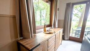 Un mostrador de madera con un florero y una bandeja, una ventana con cortinas, y vistas a muebles de exterior.