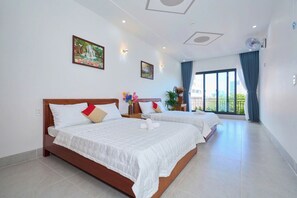 A hotel room with two beds, a large window with a view, and a ceiling fan. - Ho Quy Ly Holiday Apartment for Family (Ho Chi Minh City)