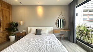 A modern bedroom with a large bed, bedside tables, a hanging light fixture, a mirror, and a view of the outside. - Ho Quy Ly Holiday Apartment for Family (Ho Chi Minh City)