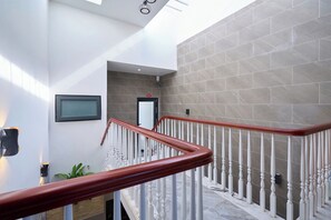 A modern interior with a staircase featuring white balusters and a wooden handrail. - Ho Quy Ly Holiday Apartment for Family (Ho Chi Minh City)