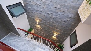 A modern interior with a marble staircase, a textured wall, and a small potted plant. - Ho Quy Ly Holiday Apartment for Family (Ho Chi Minh City)