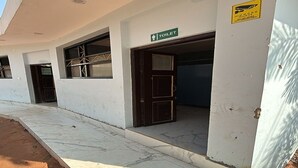 Entrada de un edificio con un letrero de baño, una puerta y una señal de precaución en la pared.
