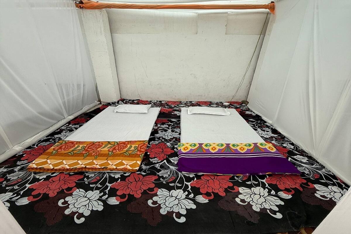 A small, enclosed tent-like room with two beds, each with a white pillow and a colorful blanket.