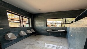 Baño público con orinales, lavamanos y suelo de baldosas.