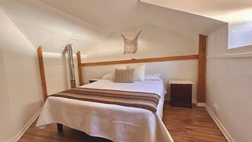 A bedroom with a bed, bedside table, and a wooden headboard.