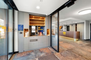 Un hall d’hôtel avec une entrée dotée d’une porte en verre, un comptoir d’accueil et un guichet d’enregistrement.