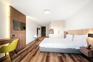 Une chambre d’hôtel moderne équipée d’un lit, d’un bureau, d’une chaise et d’un téléviseur.