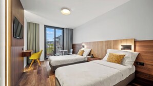 Een hotelkamer met twee bedden, een televisie, een bureau en een stoel.