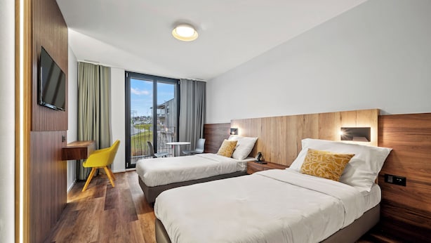 Een hotelkamer met twee bedden, een televisie, een bureau en een stoel.