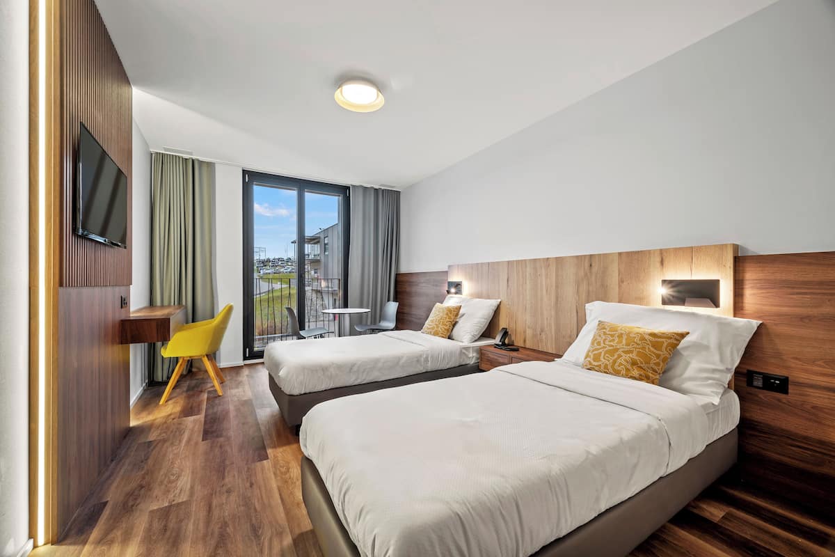 Una habitación de hotel con dos camas, televisión, escritorio y una silla.