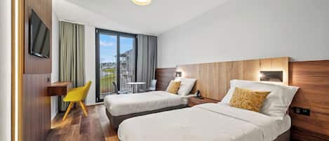 Una habitación de hotel con dos camas, televisión, escritorio y una silla.