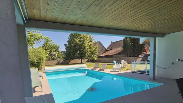 Une piscine extérieure couverte, avec vue sur les maisons au loin.