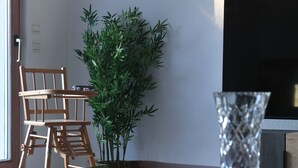 Une chaise en bois, une plante en pot et un vase en verre sur une table.