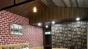 Un dormitorio con pared de ladrillo, cama, estantería y calefactor.