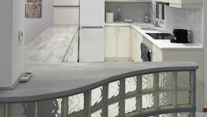 A modern kitchen with white cabinets, a refrigerator, and a countertop with a coffee maker.