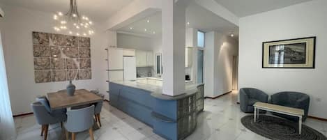 Amplia sala de estar con mesa de comedor, sofá azul y un banco.