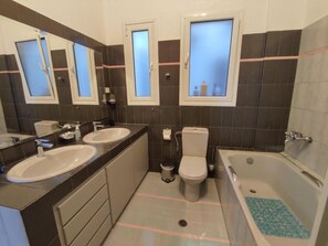 Une salle de bain moderne avec deux lavabos, des toilettes et une baignoire.