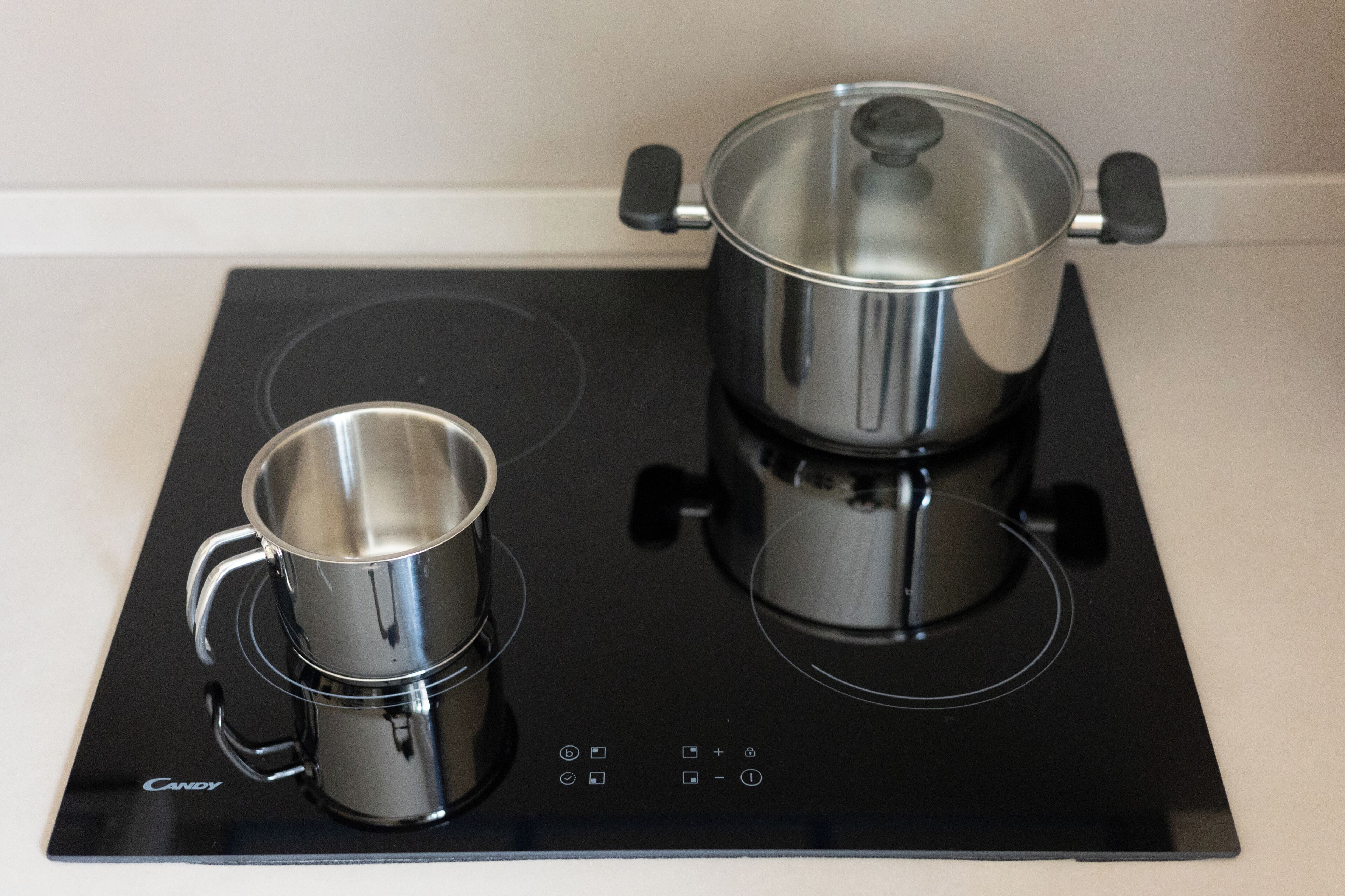 A black induction cooktop with two stainless steel pots and a coffee maker.