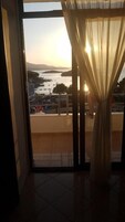 A room with a large window overlooking a body of water and a distant landscape.