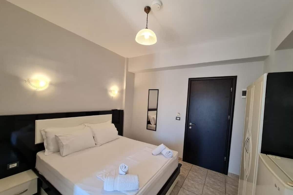 A hotel room with a bed, bedside table, wardrobe, and a door.