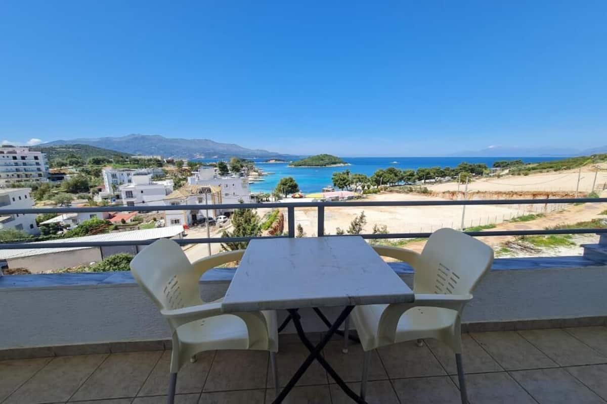 A balcony with a table and chairs overlooking a coastal view.