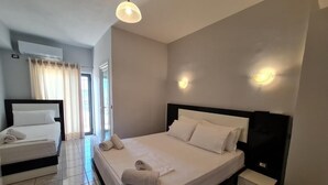A hotel room with a large bed, a bedside table, and a window with curtains.