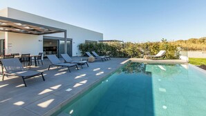 A modern outdoor pool area with lounge chairs and a dining setup.