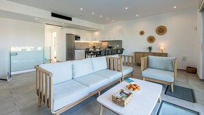 A modern living room with a sofa, a coffee table with bread, and a kitchen in the background.