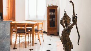 A dining area with a wooden table and chairs, a wooden cabinet, and a statue on the wall. - Palmaria suite, charming 1 bedroom apartment in delightful Genova with AC, WIFII (Genova)