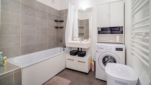 Une salle de bain moderne équipée d’une baignoire, d’un lave-linge et d’un sèche-linge.