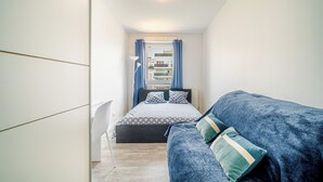 Une chambre à coucher avec un lit, un canapé bleu et une armoire blanche.