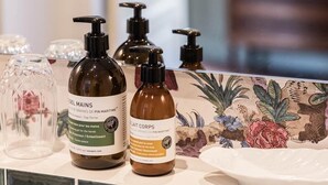 A bathroom counter with various toiletries including bottles of body wash and lotion. - Deluxe double room (Le Pian-Médoc)