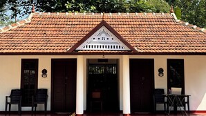A traditional building with a tiled roof, a central entrance with a decorative triangular pediment, and two doors on either side. - Beach Front Home in Marari : Marari Helen Villa (Mararikulam)
