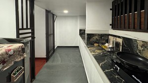 A narrow kitchen with a black stove, a refrigerator, and a microwave. - Beach Front Home in Marari : Marari Helen Villa (Mararikulam)